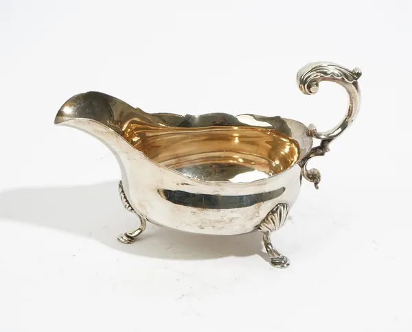 An early  George III silver sauce boat, having a scroll handle, shaped rim and raised on three shell capped feet, London probably 1764, maker William