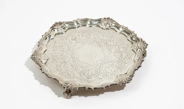 A silver salver of shaped rectangular form, later decorated to the centre within a scroll and scalloped border, raised on three scrolled feet, diamete