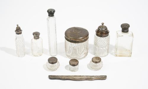 A silver twin handled trophy cup, nine various silver topped cut glass bottles and jars, a silver mounted dressing mirror and hairbrush and a comb mou