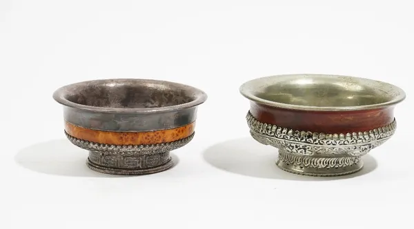 A Tibetan burl wood and white metal mounted bowl, decorated with mythological animals on a circular foot, 13cm diameter, and another later example, 14