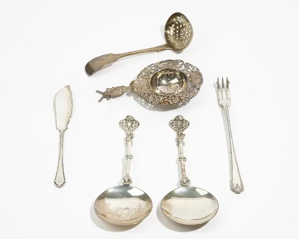 Silver, comprising; a pair of spoons, having circular bowls and with cast decoration to the handles, London 1897, a tea strainer, the handle formed as