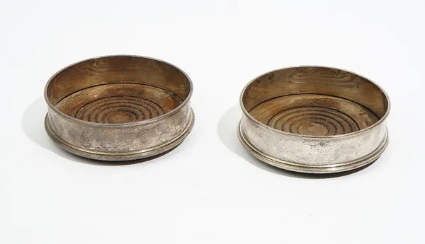 A pair of silver mounted circular bottle coasters, having turned wooden bases, London 1977, diameter 12.5cm.