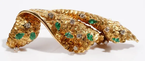 A 14ct gold, diamond and emerald-set brooch  of abstract handkerchief design  The textured gold brooch claw-set with pear-cut  emeralds and circular-c