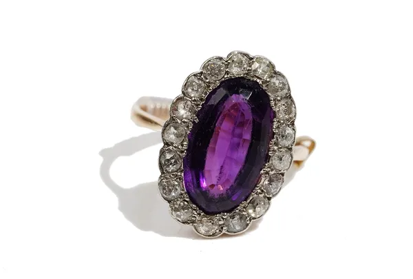 An amethyst and diamond-set dress ringOf oval cluster design, the oval mixed-cut amethyst in asurround of circular-cut diamonds, approximate totaldiam