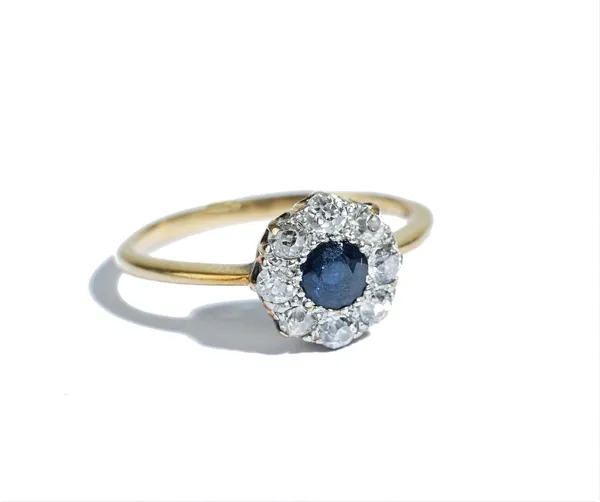 A gold, sapphire and diamond set nine stone cluster ring, mounted with the cushion shaped sapphire at the centre, in a surround of eight cushion shape