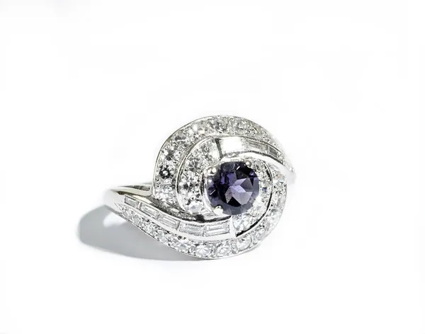 A diamond and iolite cluster ring, claw set with the circular cut iolite to the centre and otherwise set with circular cut and baguette diamonds, in a