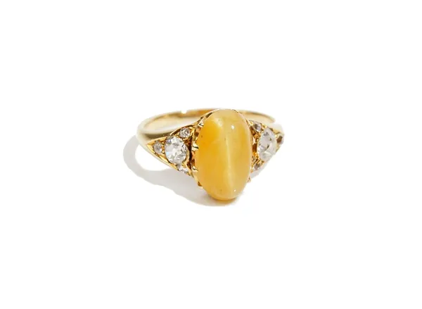 A cat's eye quartz and diamond-set dress ring, to oval cabochon cat's eye quartz, claw-set with old mine-cut diamonds to the shoulders, in a yellow pr