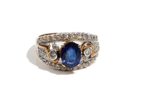 A gold, sapphire and diamond ring, in a tapered panel shaped design, claw set with an oval cut sapphire and otherwise set with circular cut diamonds,