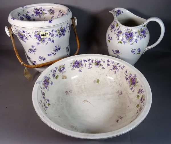 An early 20th century ceramic wash set comprising a jug and bowl and slop bucket, decorated with blue flowers, (3).