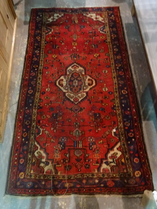 A Hamadan rug, Persian, the madder field with an ivory medallion, 191cm x 101cm.