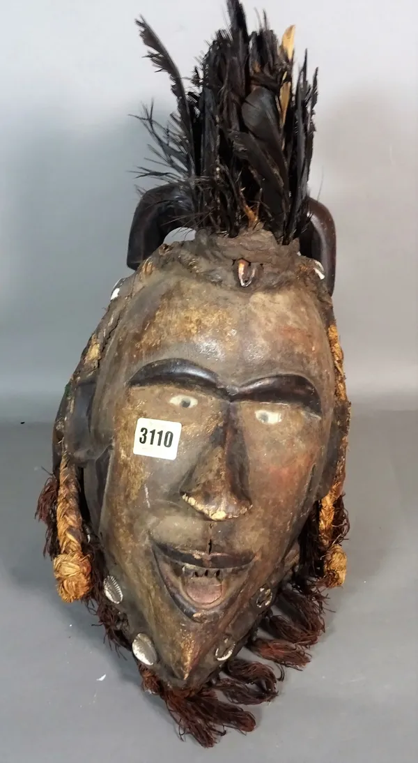 A modern tribal mask with feather plume and shell decoration, 46cm high.