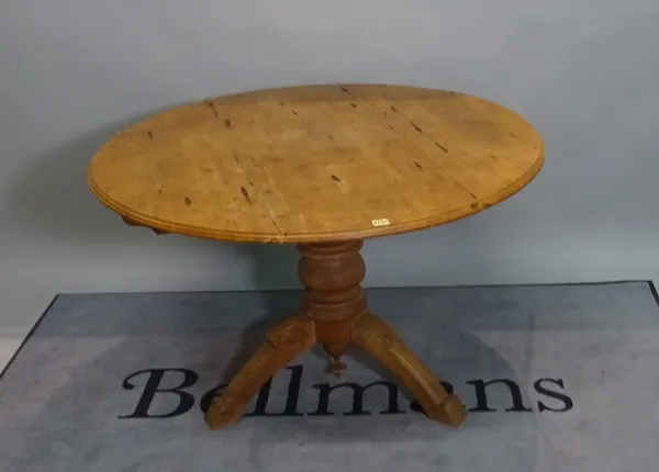 An early 20th century pine circular dining table on turned column and three downswept supports, 111cm dia x 76cm high.