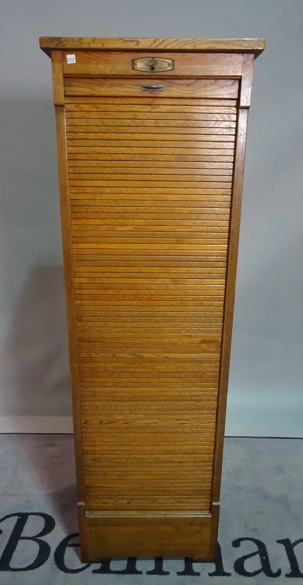 A mid-20th century oak floor standing filing cabinet, with tambour fronted sliding door, 48cm wide x 151cm high.