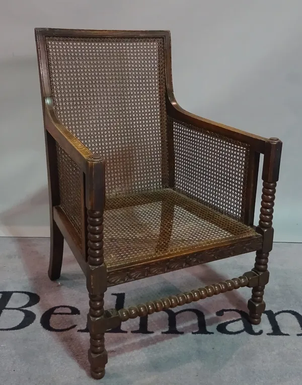 A 19th century oak framed bergere chair on bobbin turned supports, 58cm wide x 96cm high.