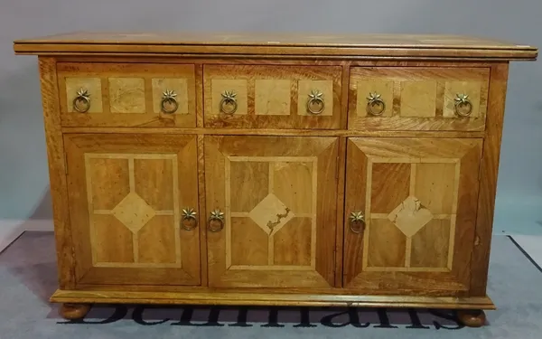 A modern oak and marble inlaid sideboard, with three short drawers over cupboard doors on bun feet, 140cm wide x 86cm high.