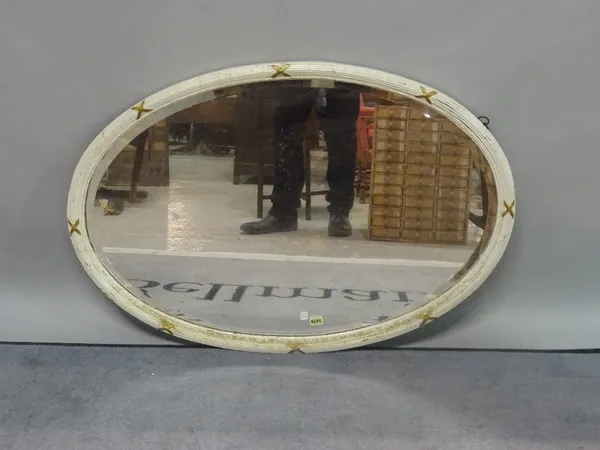 A modern white and parcel gilt decorated oval wall mirror, with bevelled glass, 105cm wide x 73cm high.