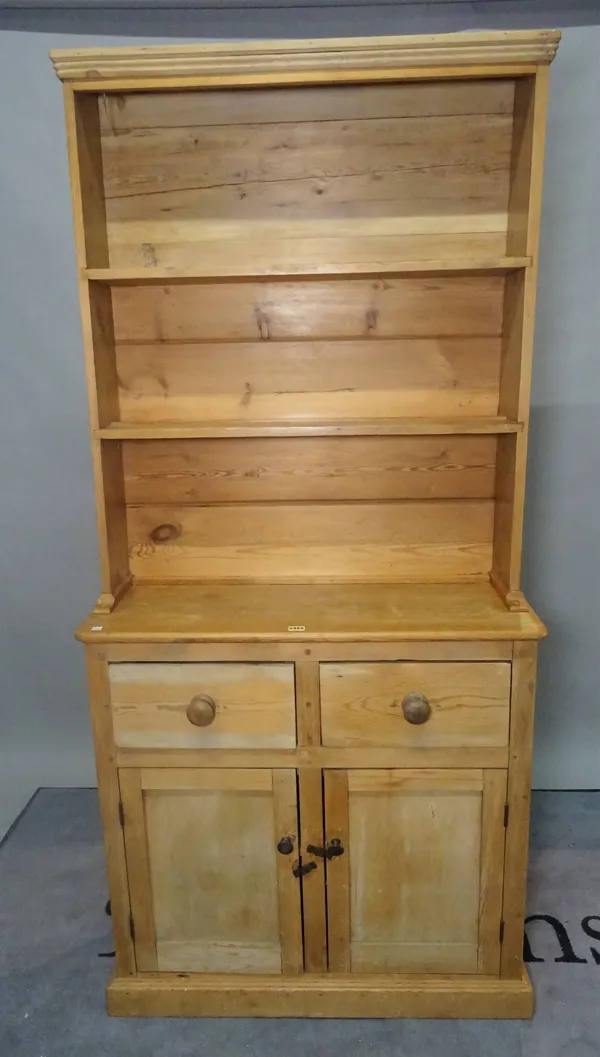 An early 20th century pine dresser, with two tier plate rack over two short drawers over a cupboard base, 89cm wide x 200cm high.