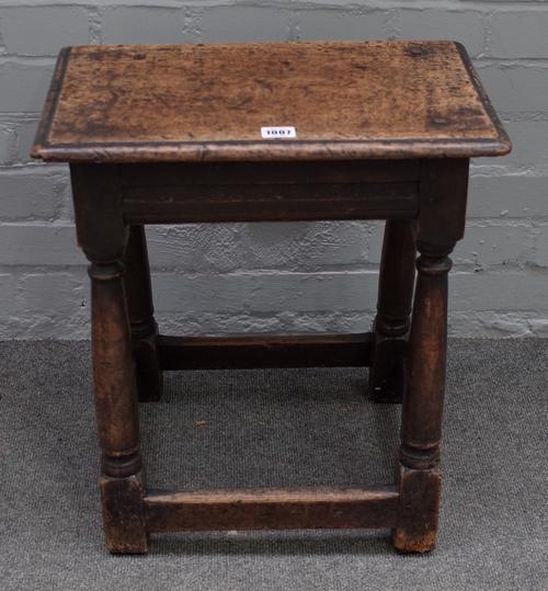 A 17th century oak joint stool, with moulded rectangular top, triangular carved friezes, on turned legs united by stretchers, 45cm wide x 51cm high.