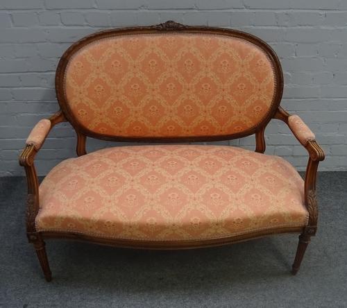 A Louis XVI style small carved walnut framed open arm sofa, on tapering fluted supports, 112cm wide x 97cm high.