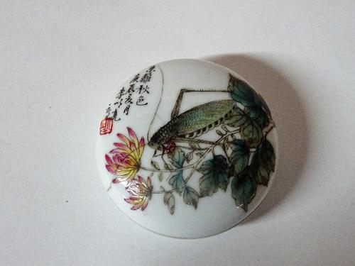 A small Chinese circular shallow box and cover, painted with a grasshopper amongst flowers beside calligraphy and a red seal, six character mark to...