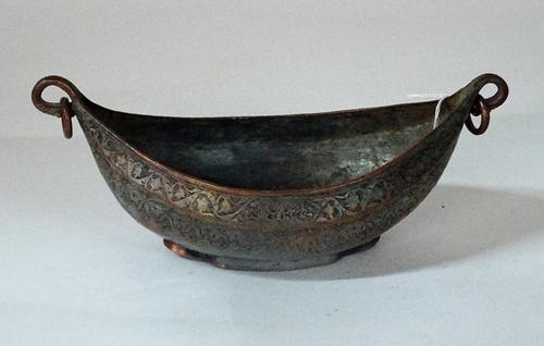 A Safavid tinned copper kachkol, possibly 18th century, of boat shape with ring handles, engraved with foliage and bearing a signature and date, 24cm...
