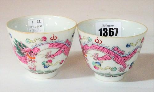 A pair of Chinese famille-rose wine cups, iron-red Qianlong seal marks but later, each enamelled with a pink-scaled dragon amongst cloud scrolls, 6cm...