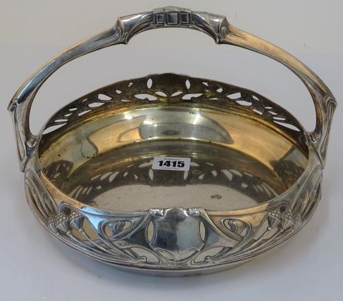 An Art Nouveau circular cake basket, detailed A.P., European, early 20th century, with fixed overhead handle, the sides foliate pierced and embossed...