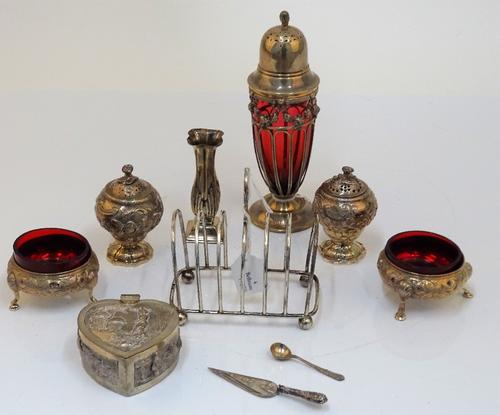 A group of silver, comprising; two similar pepperettes, London 1818 and London 1874, a silver mounted cranberry coloured glass sugar caster,...
