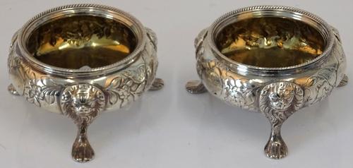 A pair of George III Irish silver cauldron salt cellars, circa 1770, maker's mark rubbed, foliate embossed around vacant cartouches, on lion mask...