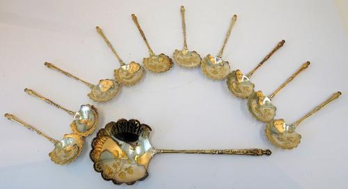 A set of ten French fruit spoons, with one matching fruit serving spoon, each of the shaped bowls engraved with fruit and with cast decoration to the...