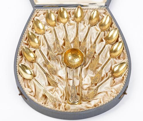 A German set of twelve gilt teaspoons with a matching pair of sugar tongs and tea strainer, detailed 800, with the original fitted case.