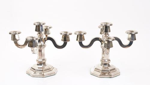A pair of foreign silver five light table candelabra, with a central light surrounded by four scrolled single light arms, raised on an octagonal...