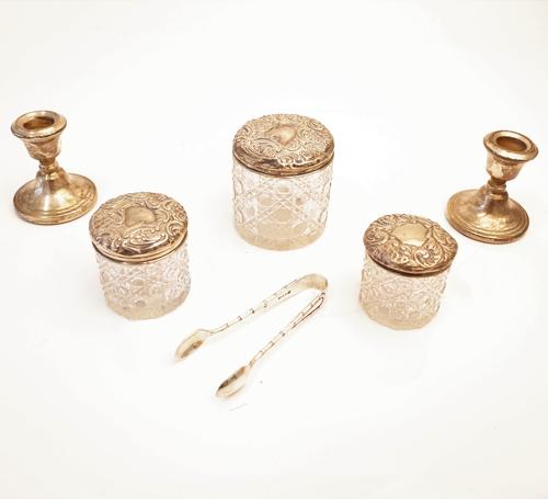 Three silver lidded faceted glass toilet jars, with embossed decoration, a pair of silver small candlesticks (loaded), Birmingham 1982, a pair of...