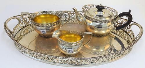 A silver three piece tea set and accompanying tray, comprising; a teapot, a twin handled sugar bowl and a milk jug, each piece with pierced...