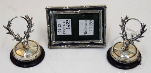 A pair of silver mounted menu holders, each formed as a stag's head on a circular turned wooden base, Birmingham 1907 and a silver mounted small...