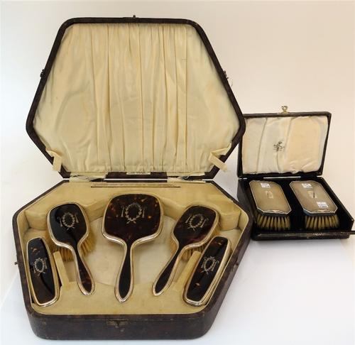 A silver mounted and tortoiseshell part dressing set, comprising; a pair of hairbrushes and a pair of clothes brushes, Birmingham 1927 and a hand...