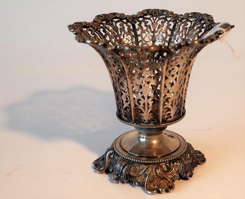 A silver coloured metal vase, probably European circa 1900, of tapered form, with scroll pierced decoration within a cast scrolled rim, raised on a...