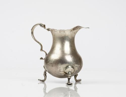 An early George III silver cream jug of baluster form having a shaped rim and raised on three pad feet, London 1763, weight 86gms.