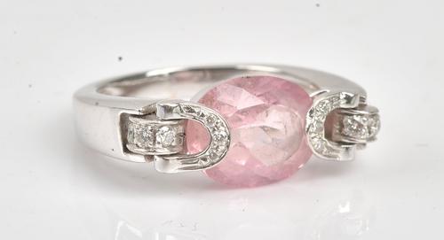 COLLECTED 06.08.2021. A diamond and pink tourmaline ring, mounted with the oval cut pink tourmaline to the centre, between diamond set loop shaped sides mounted with...