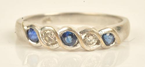 A white gold, sapphire and diamond set five stone ring, mounted with three circular cut sapphires alternating with two circular cut diamonds,...