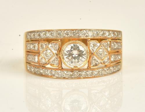 A gold and diamond ring, in a pierced panel shaped design, mounted with circular cut diamonds and with the principal diamond mounted at the centre,...