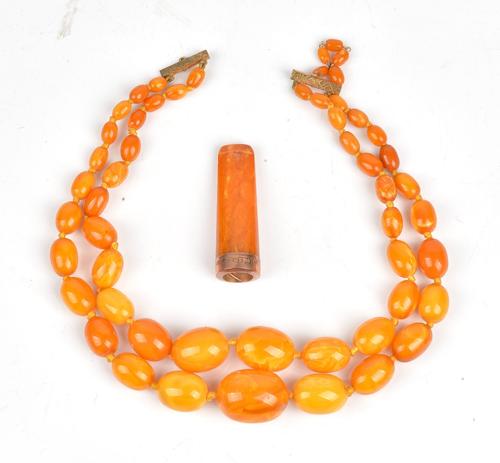 A two row necklace of varicoloured mottled butterscotch coloured graduated opaque oval amber beads, with a base metal clasp, gross weight 62 gms and...