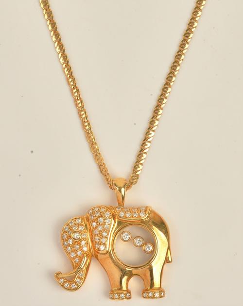 A gold and diamond pendant designed as a standing elephant, the body glazed with three floating circular cut diamonds and otherwise further set with...