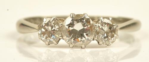 A white gold and platinum diamond set three stone ring, claw set with a row of circular cut diamonds and with the principle diamond mounted at the...