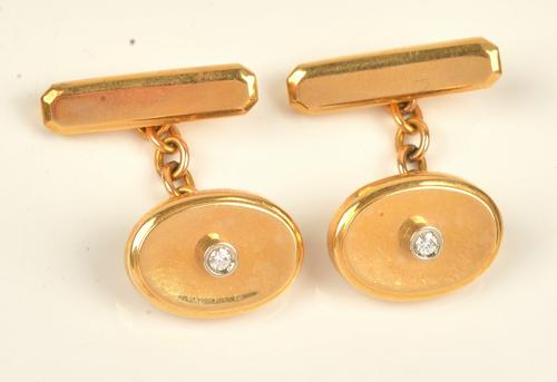A pair of gold and diamond set cufflinks, each oval front of dished form, mounted with a circular cut diamond to the centre, the backs with bar...