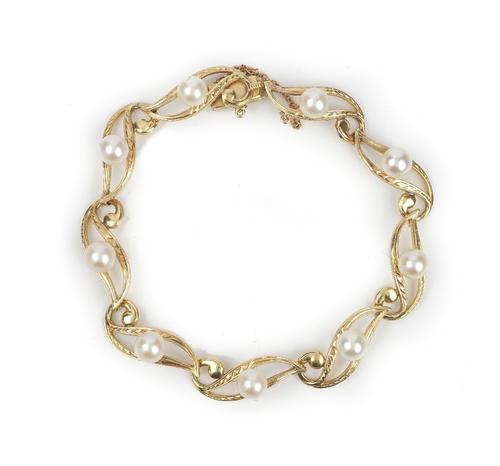 A gold and cultured pearl bracelet, in a pierced and engraved serpentine link design, mounted with cultured pearls at intervals, on a snap clasp,...