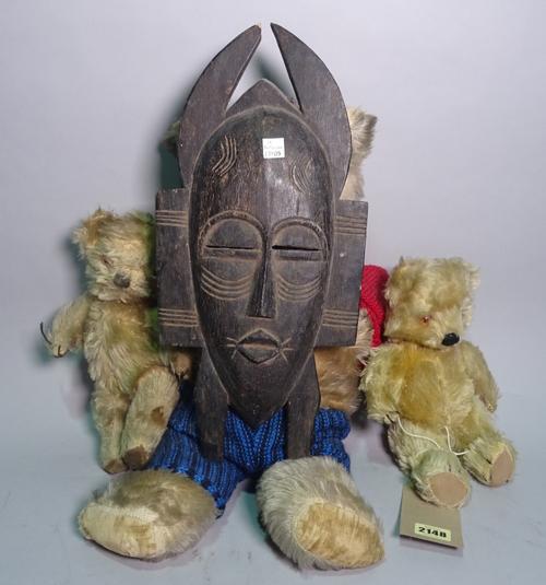 A group of three early 20th century mohair Teddy bears, the largest 53cm long, and an early 20th century African hardwood mask, 41cm high.