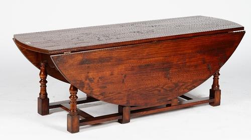 A 17th century style oak low gateleg table, with hinged oval top and two end drawers, on baluster turned legs, 153cm wide x 53cm high.