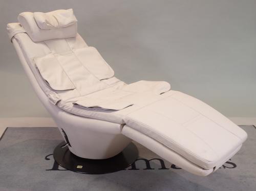 A modern reclining/massage low armchair with faux white leather on circular revolving metal base, 165cm wide x 90cm high.