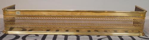 A 19th century brass fire fender, 126cm wide, together with a cast iron fire back, (2).